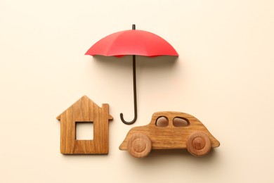 Photo of Mini umbrella, house model and toy car on beige background, flat lay