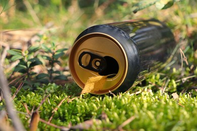 Photo of Used aluminium can on green grass outdoors, closeup. Recycling problem