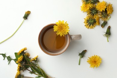 Photo of Delicious fresh tea and beautiful dandelion flowers on white background, top view