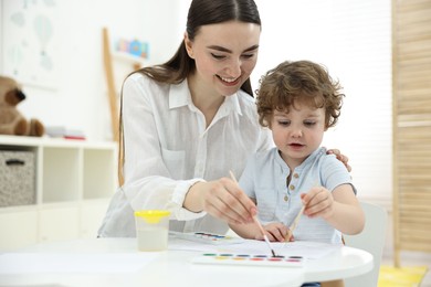 Mother and her little son painting with watercolor at home