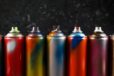 Photo of Used cans of spray paint on black marble background