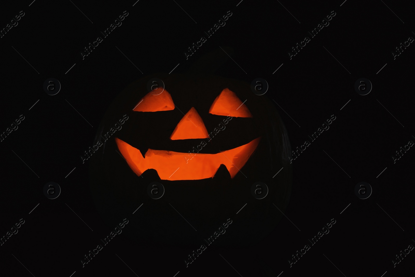 Photo of Halloween pumpkin head. Glowing jack lantern in dark