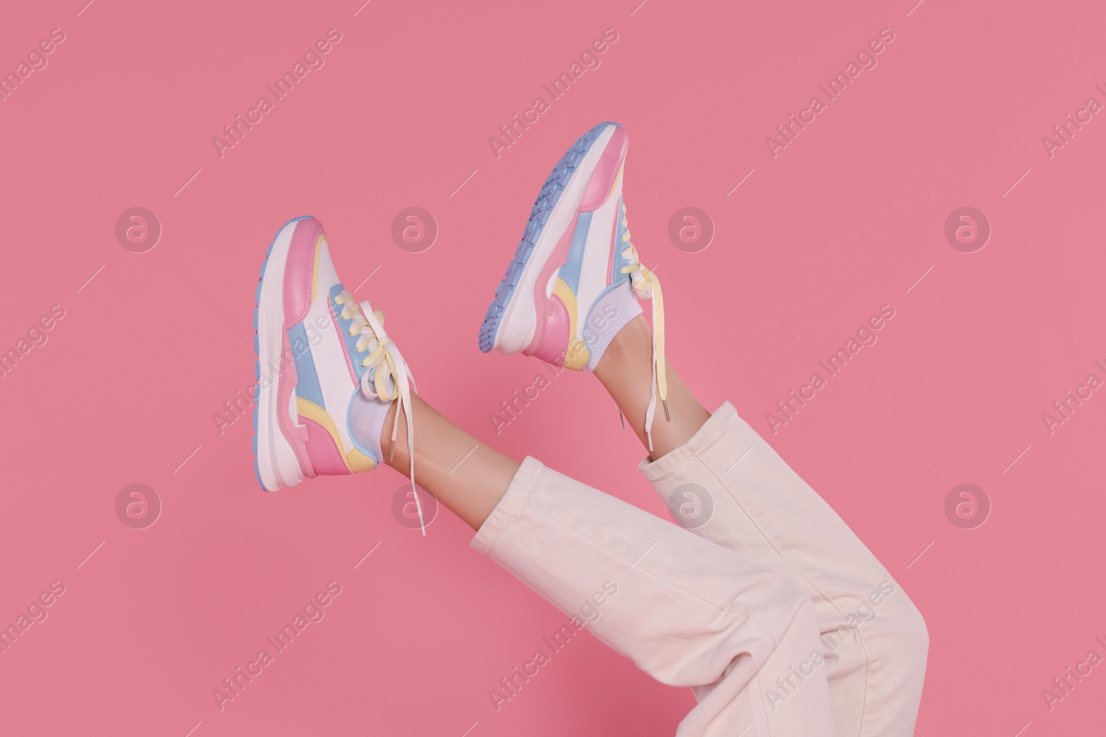 Photo of Woman wearing pair of new stylish sneakers on pink background, closeup