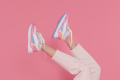 Photo of Woman wearing pair of new stylish sneakers on pink background, closeup