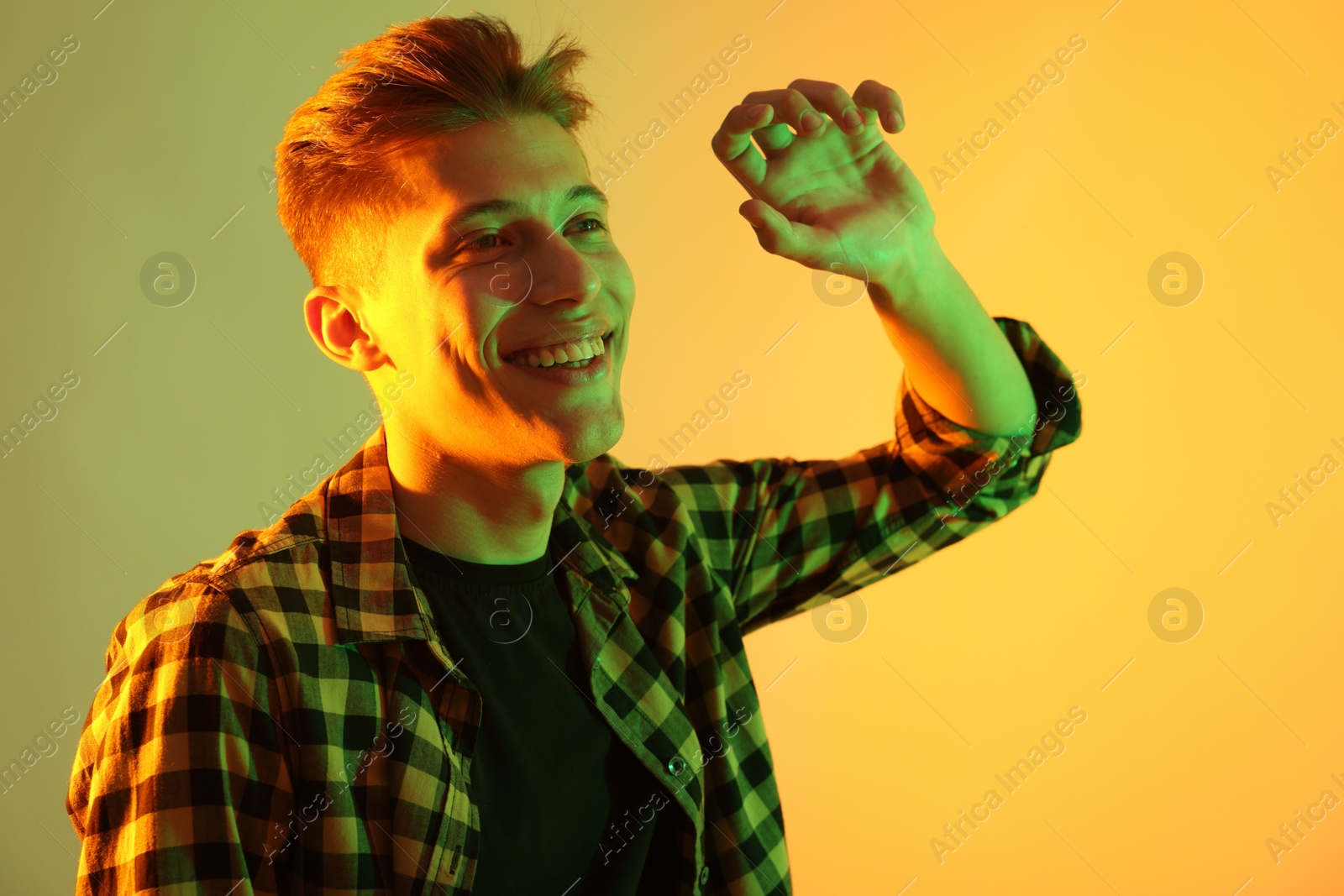 Photo of Young man dancing on color background in neon lights