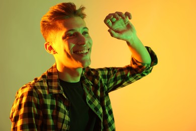 Young man dancing on color background in neon lights