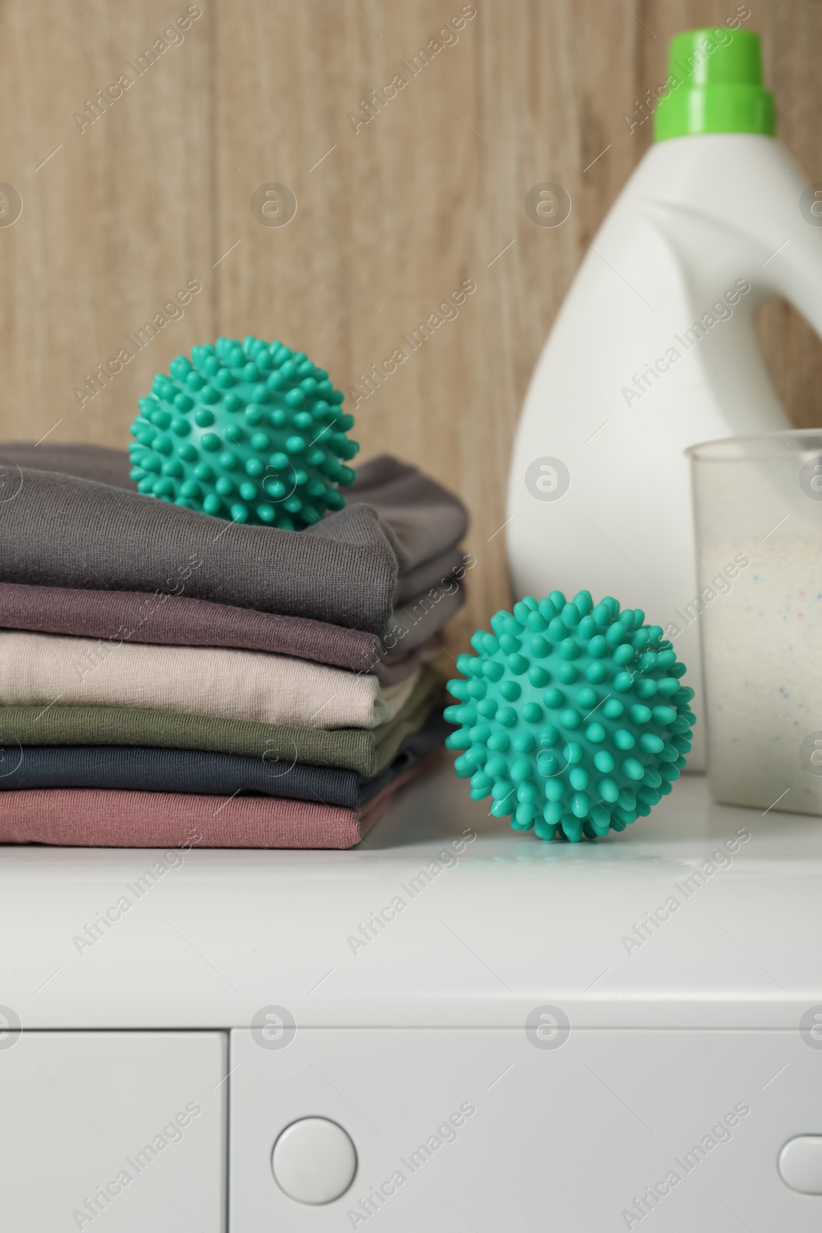 Photo of Dryer balls, stacked clean clothes and detergents on washing machine