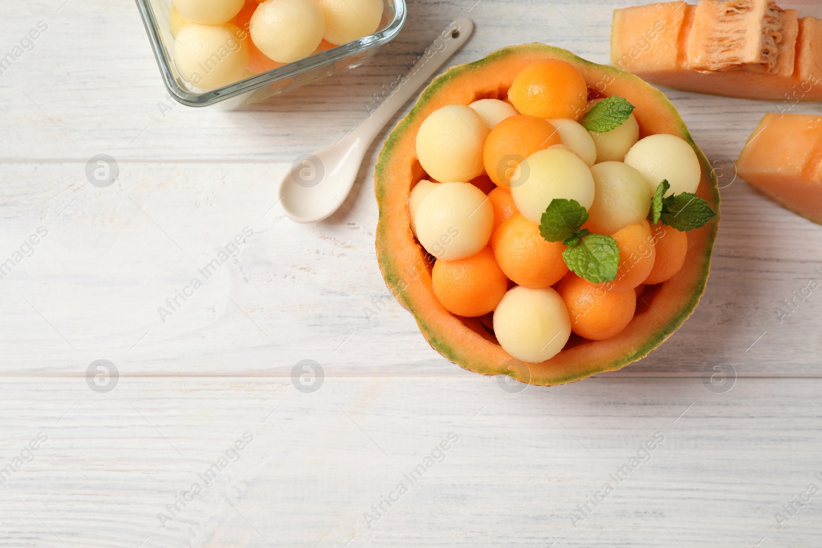 Photo of Different melon balls with mint on white wooden table, flat lay. Space for text