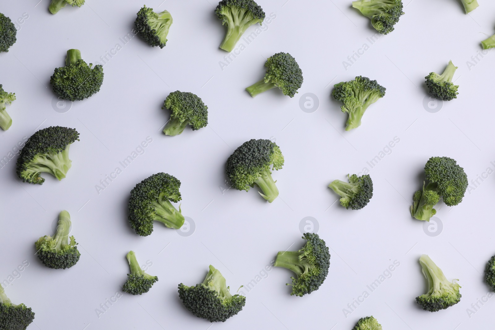 Photo of Many fresh green broccoli pieces on white background, flat lay