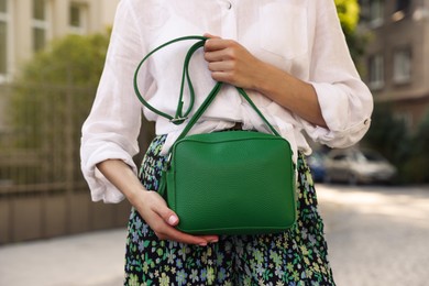 Photo of Woman with stylish green bag on city street, closeup