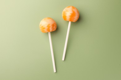 Photo of Tasty lollipops on green background, flat lay