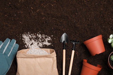 Photo of Flat lay composition with gardening tools and chemical fertilizer on soil. Space for text