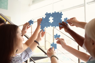 Photo of People with puzzle indoors, closeup of hands. Unity concept