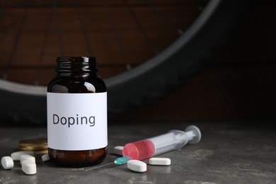 Photo of Pills, syringe and bike wheel on grey table. Using doping in cycling sport concept