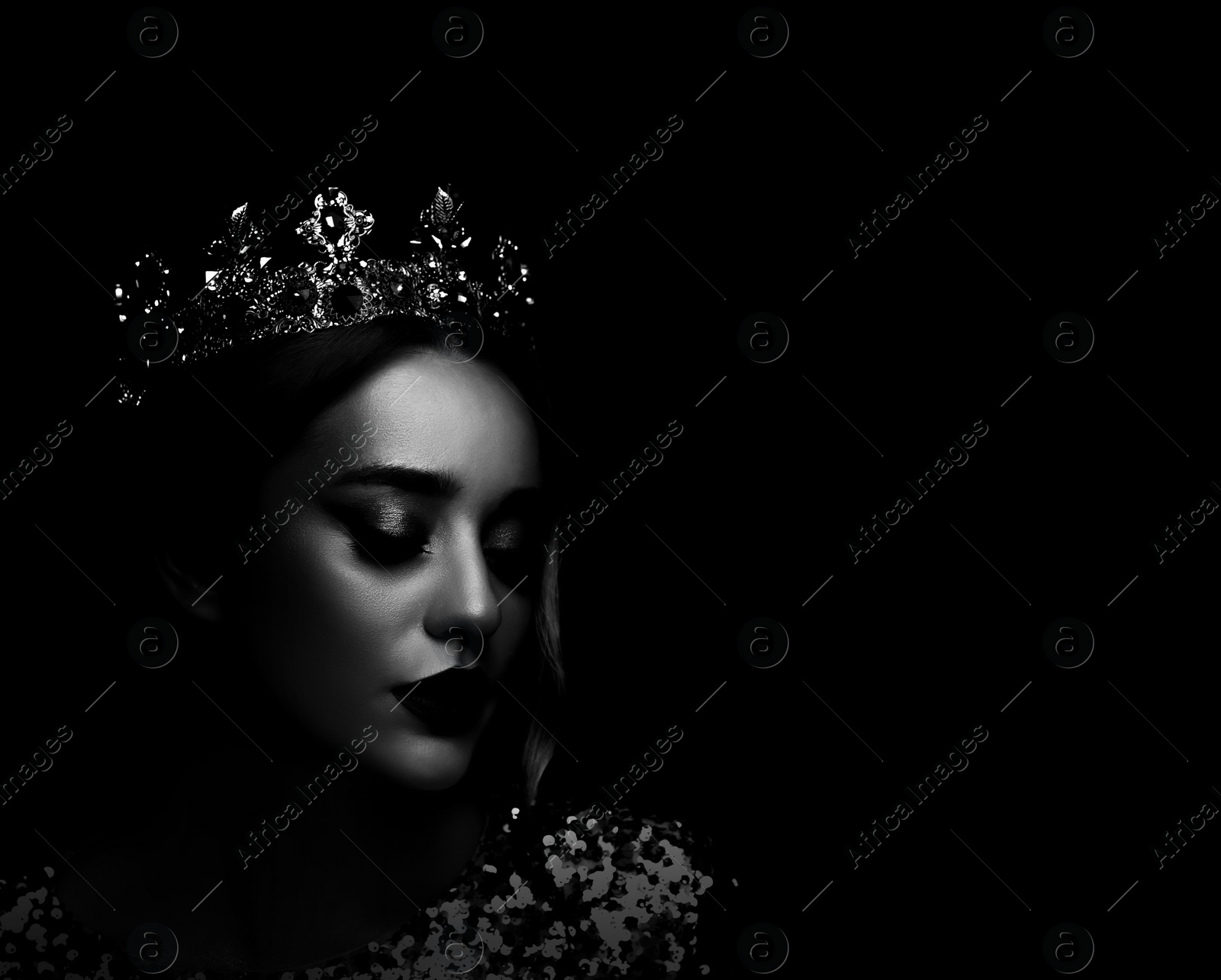 Image of Silhouette of woman with crown in darkness. Portrait on black background