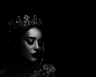 Silhouette of woman with crown in darkness. Portrait on black background