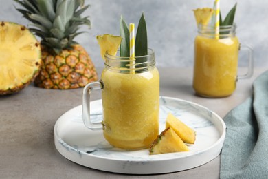 Photo of Tasty pineapple smoothie and sliced fruit on light grey table