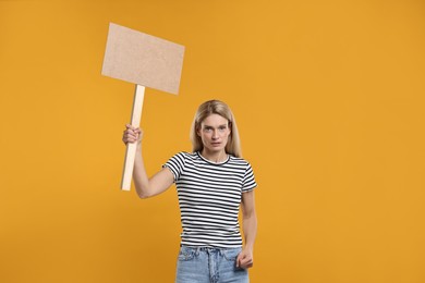 Woman holding blank sign on orange background, space for text