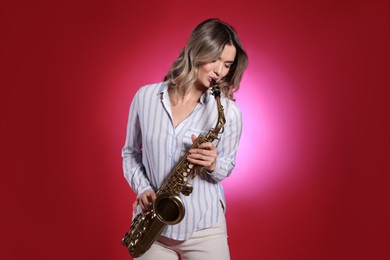 Photo of Beautiful young woman playing saxophone on red background
