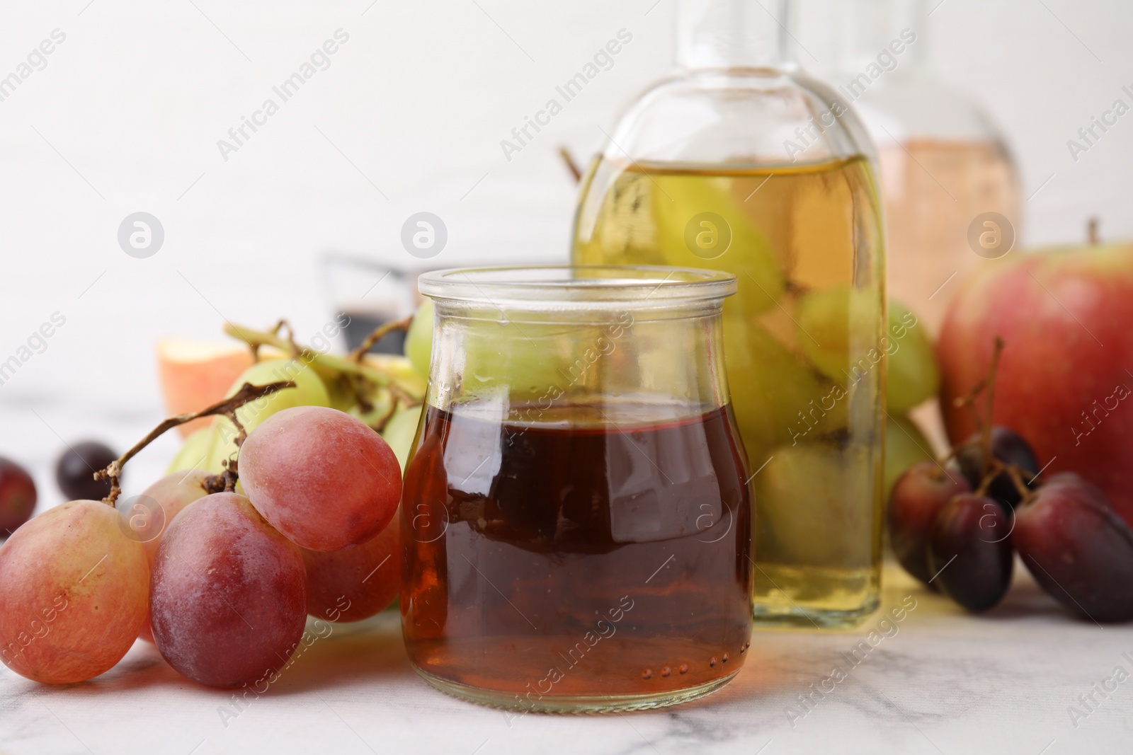 Photo of Different types of vinegar and ingredients on light marble table, closeup