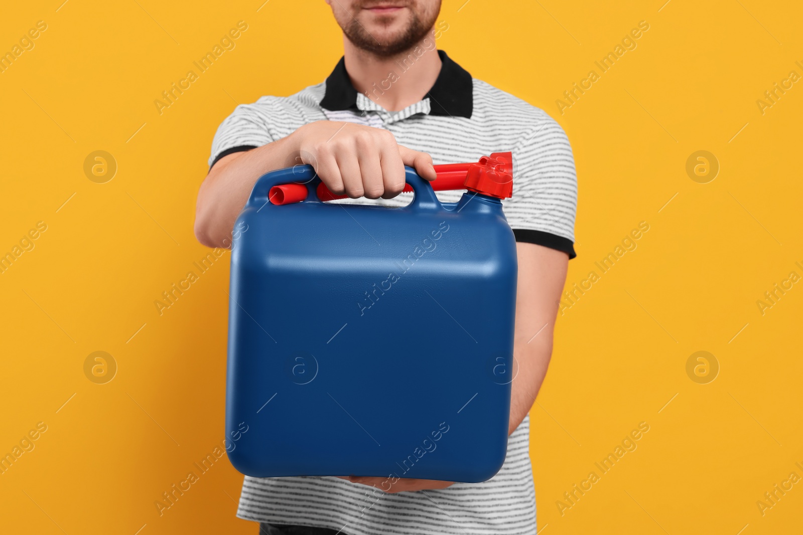 Photo of Man holding blue canister on orange background, closeup
