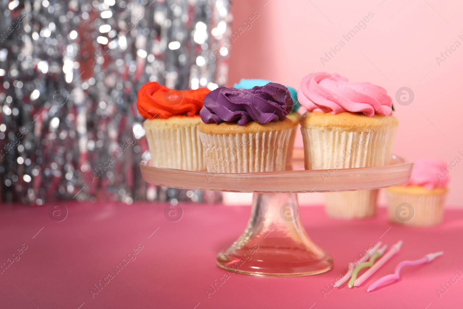 Photo of Delicious cupcakes with bright cream and candles on pink table, space for text