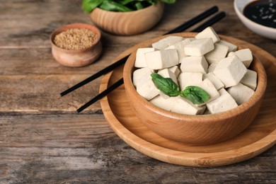 Photo of Delicious tofu with basil and chopsticks on wooden table