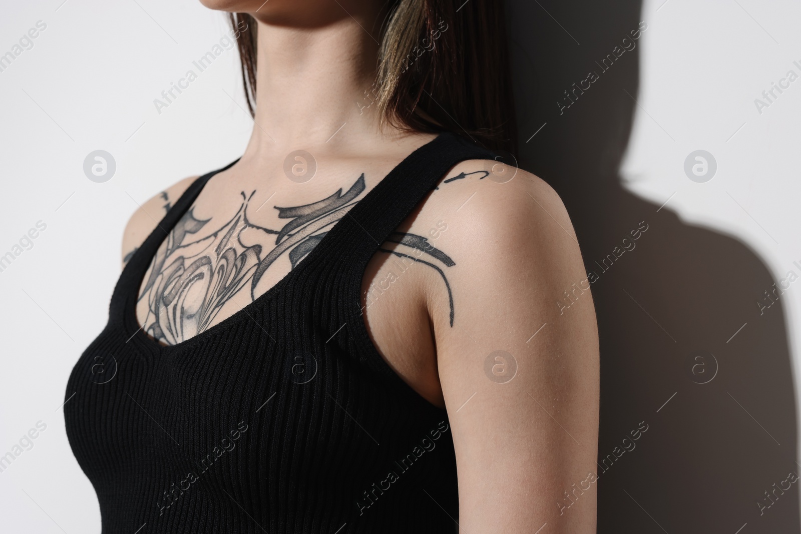 Photo of Woman with cool tattoos on light background, closeup