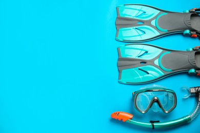 Photo of Pair of turquoise flippers and mask on light blue background , flat lay. Space for text
