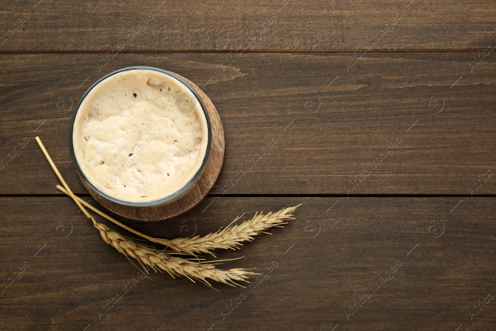 Photo of Leaven and ears of wheat on wooden table, flat lay. Space for text