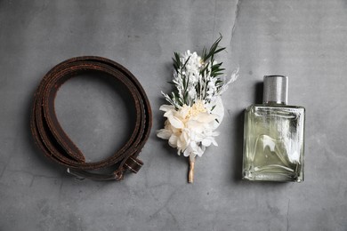 Wedding stuff. Stylish boutonniere, belt and perfume bottle on gray background, flat lay