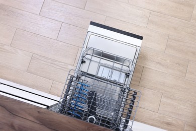 Open clean empty dishwasher in kitchen, top view