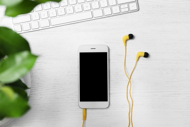 Photo of Flat lay composition with headphones, smartphone and computer keyboard on white wooden background. Space for text