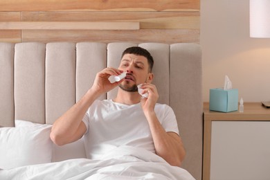 Photo of Ill man using nasal spray in bed at home