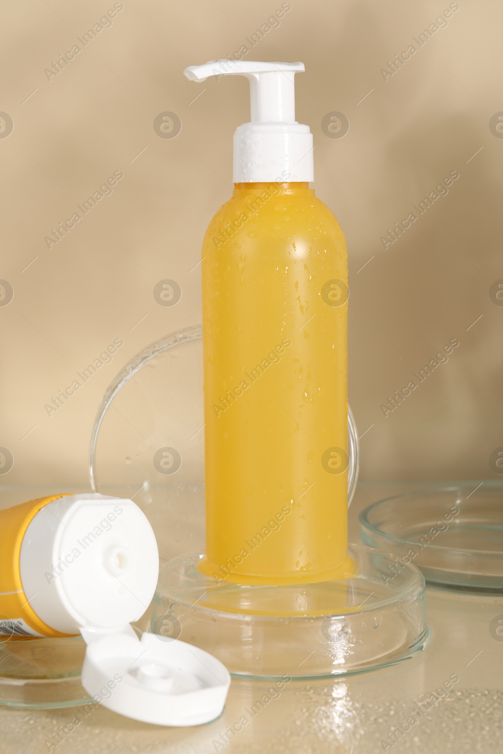 Photo of Wet face cleansing products and petri dishes on beige background