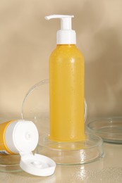 Wet face cleansing products and petri dishes on beige background