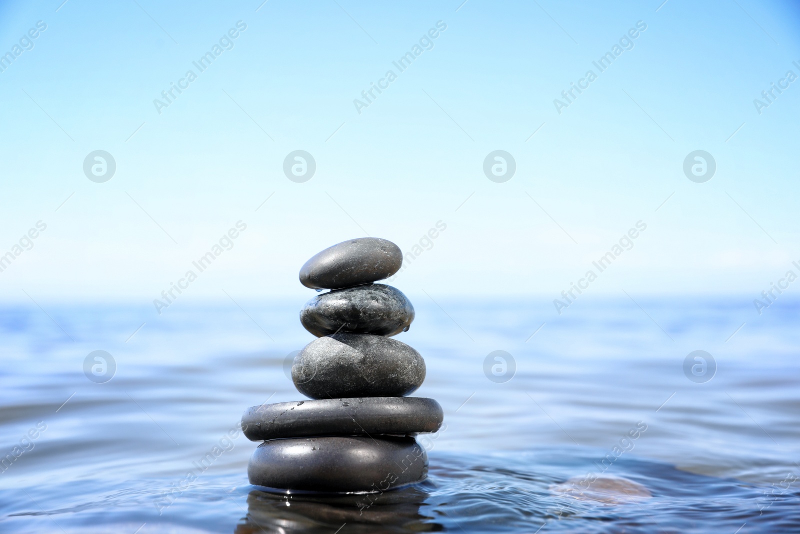 Photo of Stack of stones in sea water, space for text. Zen concept