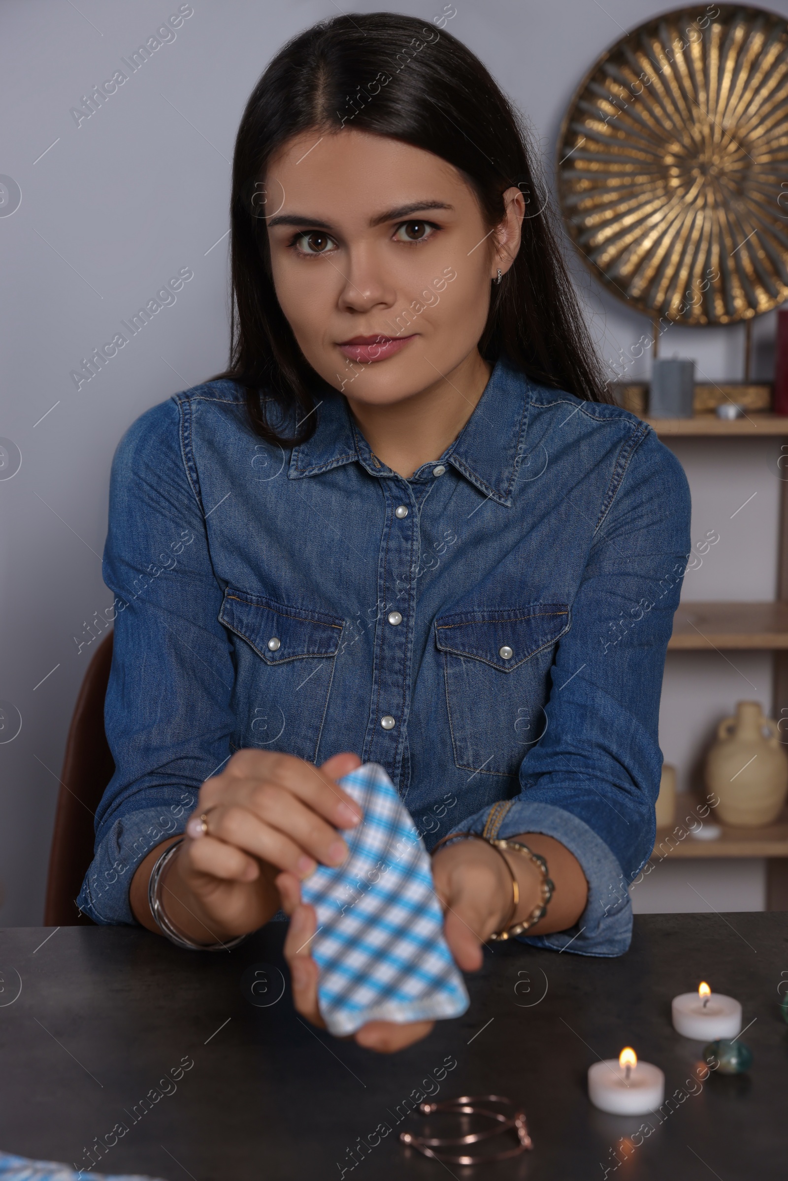 Photo of Fortune teller with deck of tarot cards at grey table indoors