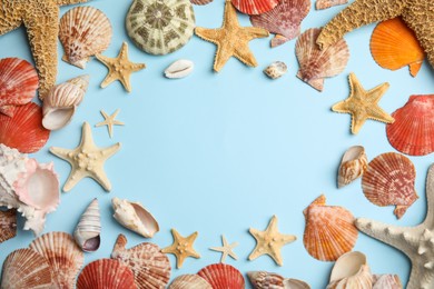 Frame of beautiful sea stars and shells on light blue background, flat lay. Space for text