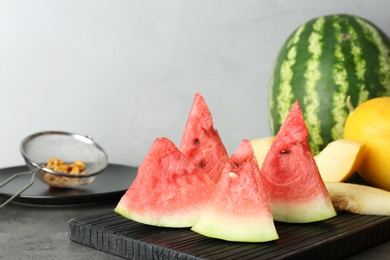 Photo of Watermelon and melon slices on cutting board against light background