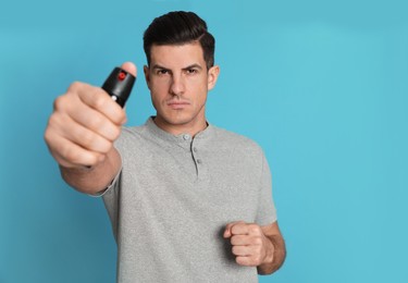 Photo of Man using pepper spray on turquoise background