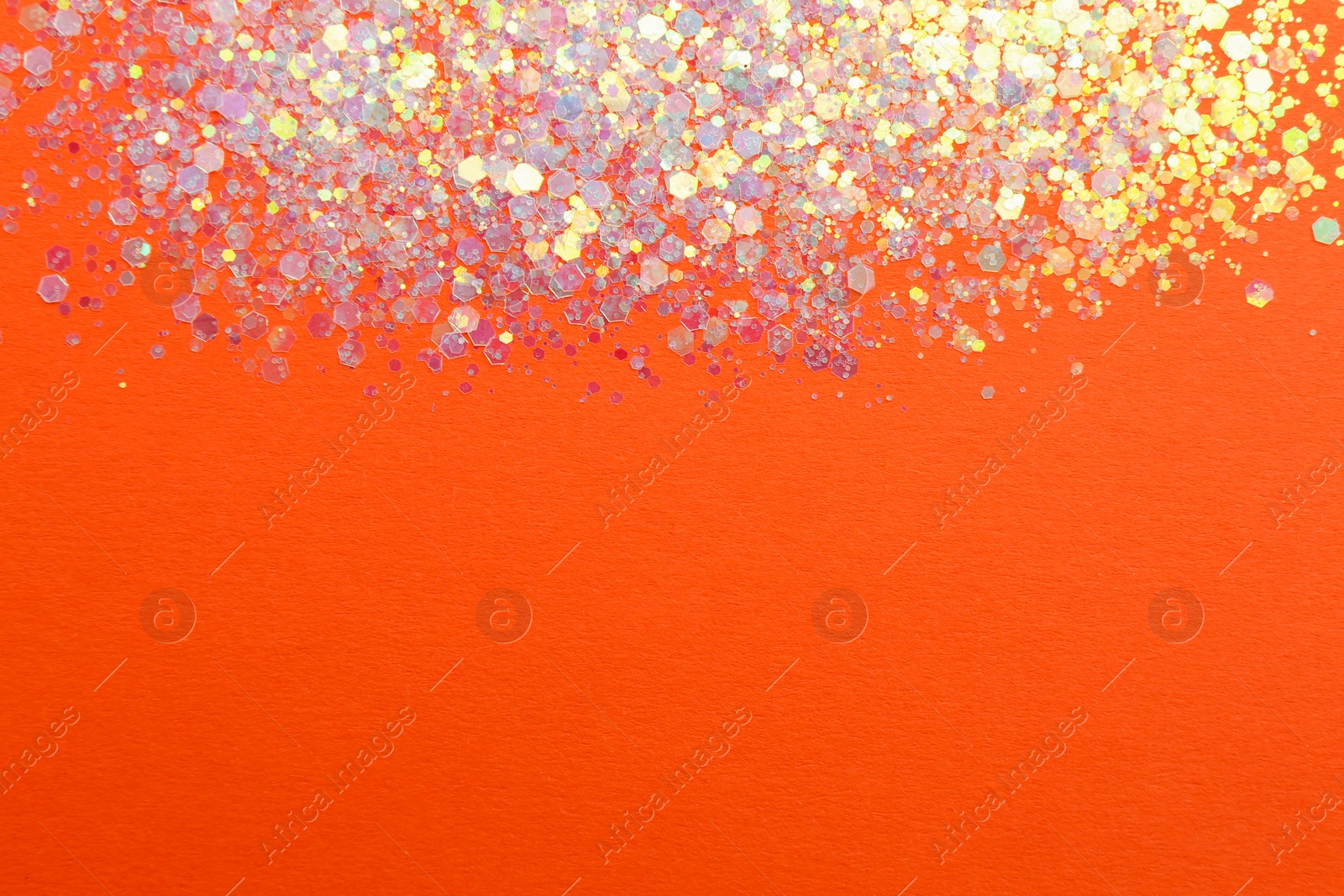 Photo of Shiny bright lilac glitter on orange background, flat lay. Space for text