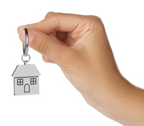 Photo of Woman holding metallic keychain in shape of house on white background, closeup