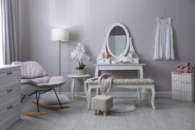 Wooden dressing table with decorative elements and makeup products in room. Interior design