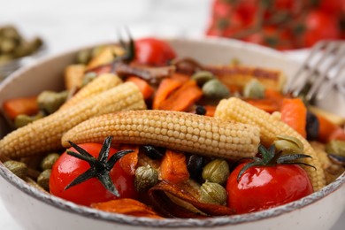 Photo of Tasty roasted baby corn with tomatoes and capers on table, closeup