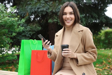 Special Promotion. Happy young woman with smartphone and cup of drink in park