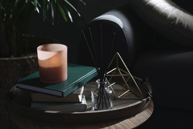 Wooden tray with decorations and books on table in room