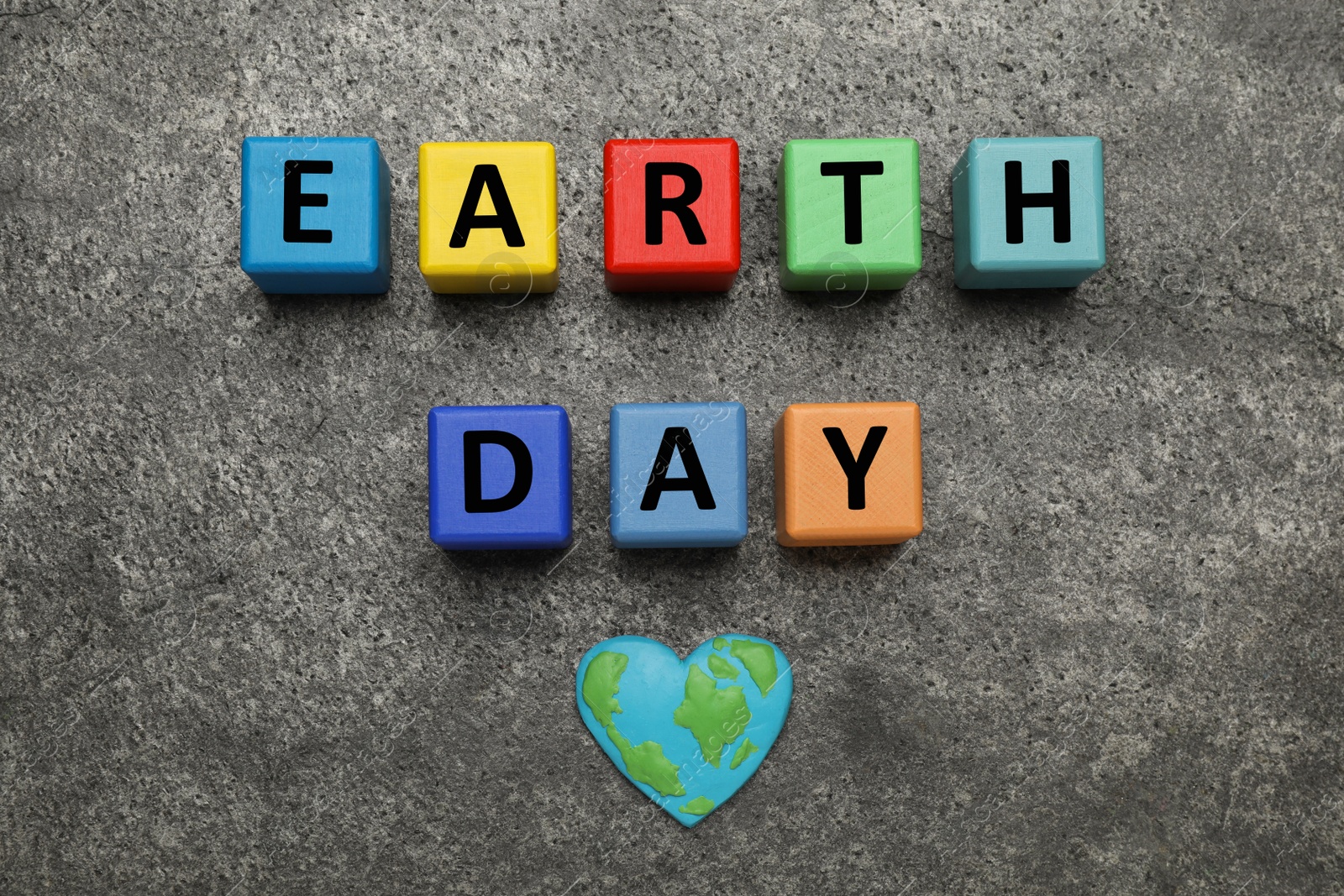 Photo of Colorful cubes with words Earth Day and heart shaped plasticine planet on grey table, flat lay