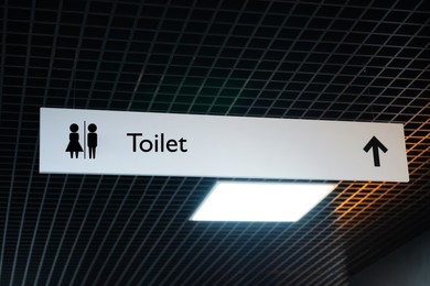 Image of Hanging sign of public toilet with arrow showing direction