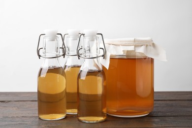 Photo of Homemade fermented kombucha in glass jar and bottles on wooden table